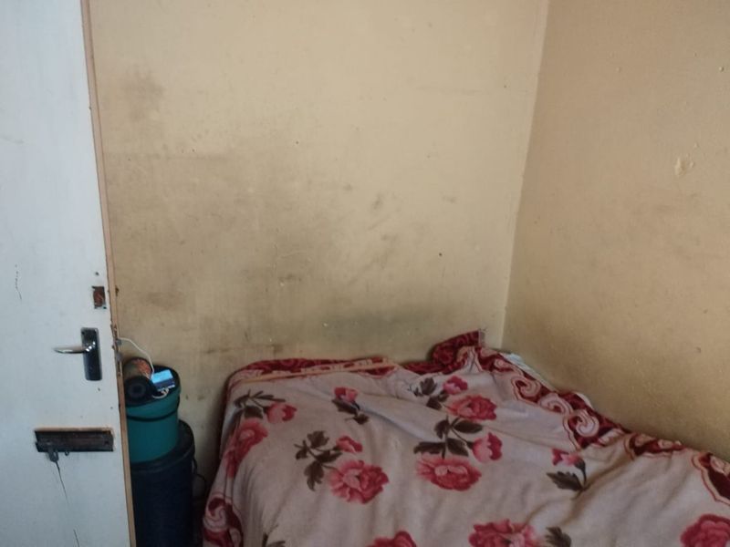 A small bedroom featuring plain walls in need of maintenance and repair.