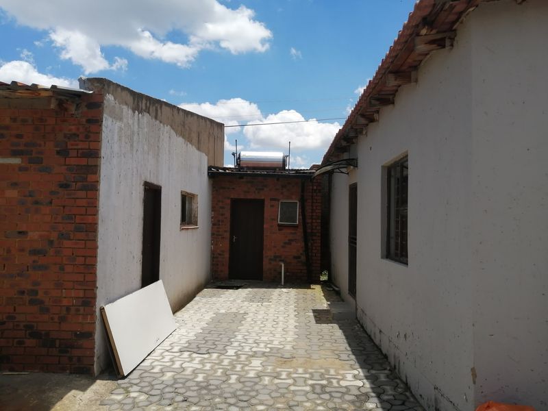 A rear courtyard area featuring paved flooring, brick and plastered wall finishes, and a roof-mounted solar water heating system.