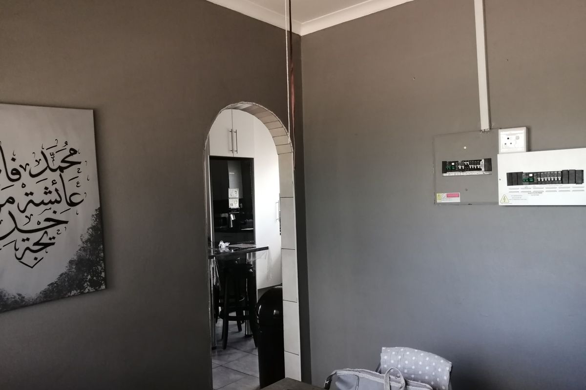 Living area featuring a decorative archway leading to the kitchen and a wall-mounted electrical distribution board.