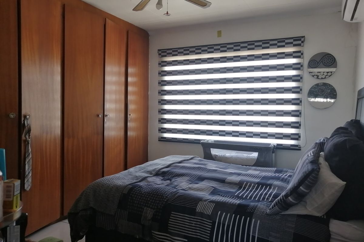 A bedroom featuring extensive built-in wooden cabinetry, a ceiling fan, and a wall-mounted air conditioning unit.