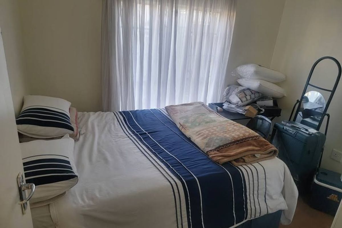 A standard bedroom featuring neutral walls and a window with installed curtain rails, providing a functional space for rest.
