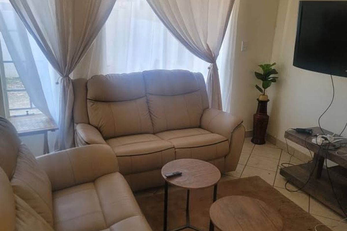 A living room area featuring ceramic floor tiles and window curtain treatments, providing a functional space for relaxation.