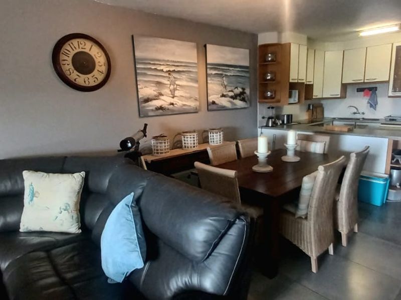 Open-plan living and dining area featuring a functional kitchen with built-in cabinetry and tiled flooring throughout.