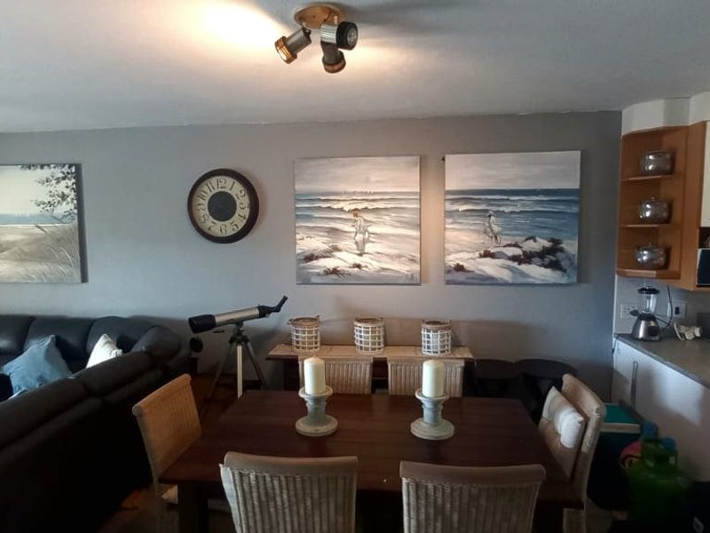 Open plan living and dining area featuring a functional kitchen with built-in cabinetry, integrated oven, and cooktop, finished with neutral wall tones.