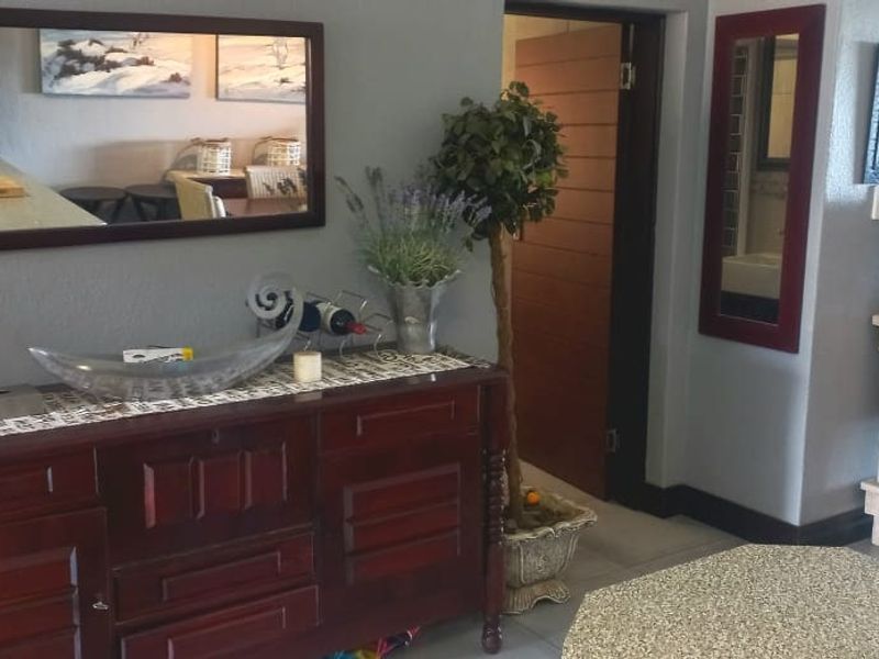 A living area featuring tiled flooring and a neutral wall finish, providing a functional space with access to adjacent rooms.