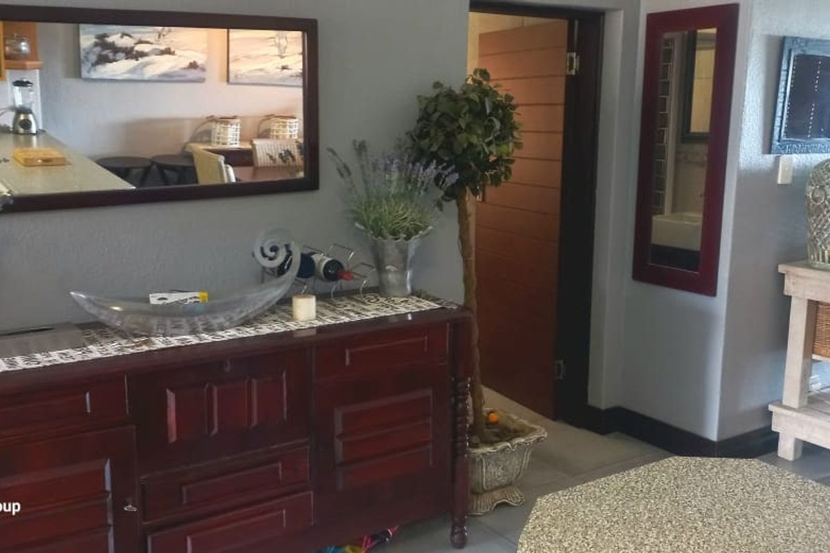 A living area featuring tiled flooring and a neutral wall finish, providing a functional space with access to adjacent rooms.