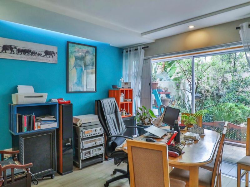 A home office space featuring laminate flooring, recessed ceiling lighting, and large sliding glass doors providing direct access to the garden area.