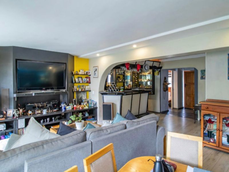 Open plan living area featuring a built-in bar, arched transition, and recessed lighting, creating a functional space for entertaining.