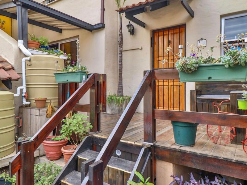 A raised timber deck patio area featuring a security gate entrance, integrated water storage tanks, and timber balustrades.