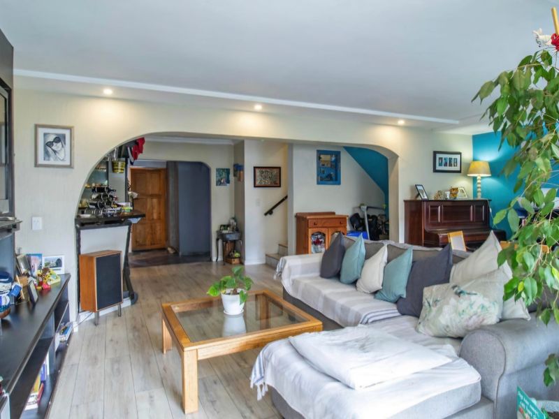 Spacious living area featuring laminate flooring, recessed lighting, and an arched architectural transition leading to the hallway and staircase.