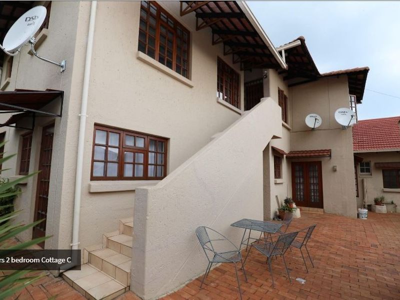Rear exterior view of the property featuring a brick-paved courtyard, external staircase leading to the upper level, and traditional timber-framed windows.