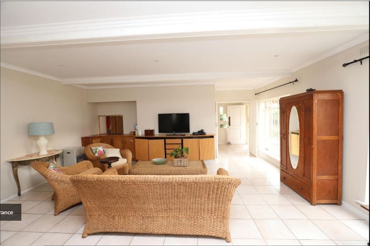 Spacious living room featuring neutral tiled flooring, built-in cabinetry, and classic cornicing, offering a bright and functional layout.