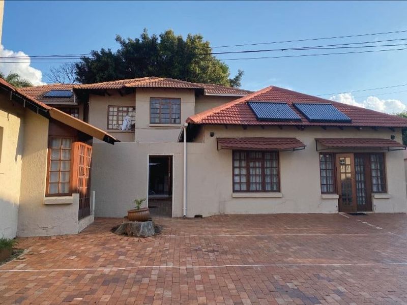 Rear view of the property featuring a brick paved courtyard, solar water heating panels, and traditional timber-framed windows and doors.