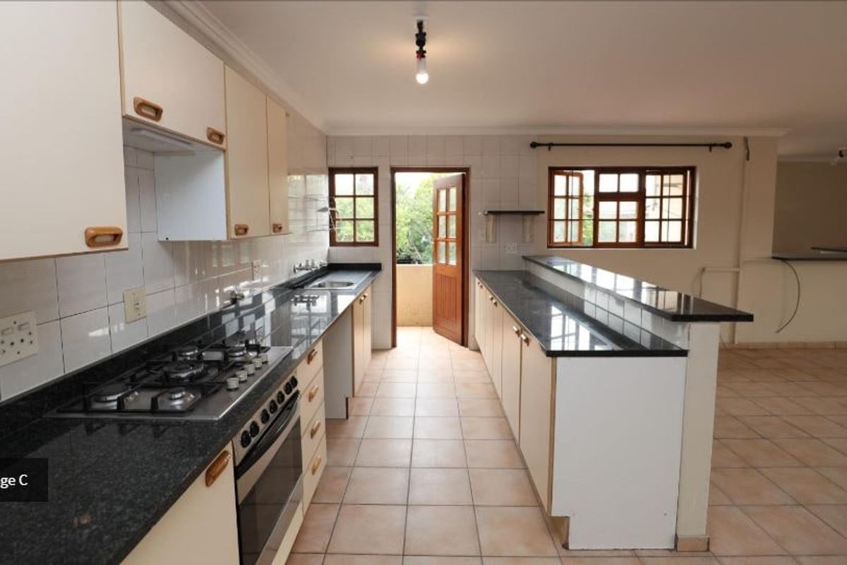 Spacious kitchen featuring granite countertops, gas hob, built-in oven, and a breakfast bar, with direct access to an outdoor area.