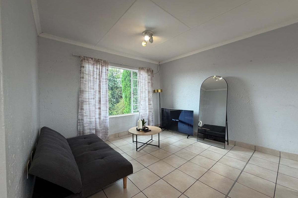 A living room featuring tiled flooring, coved ceilings, and a large window providing natural light.