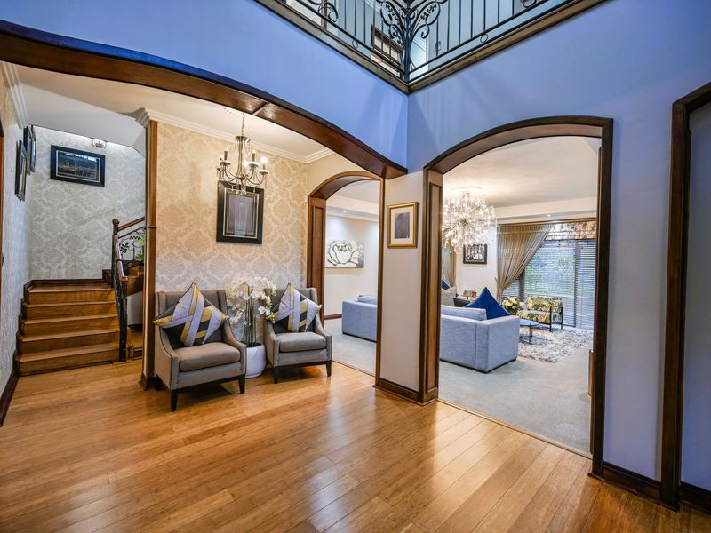 Spacious grand entrance hall featuring hardwood flooring, elegant arched doorways, and a striking wrought iron balustrade overlooking the foyer.