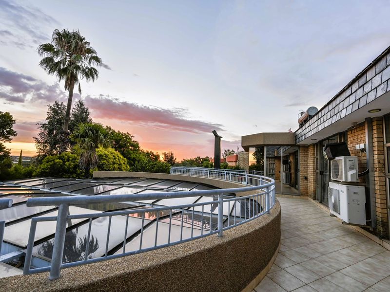 Spacious curved balcony featuring tiled flooring, metal railings, and views, providing an ideal outdoor space for relaxation and entertaining.