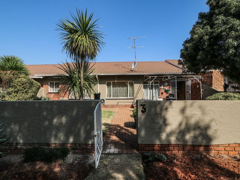Front view of a single-story apartment unit featuring a brick facade, tiled roof, and a private gated entrance with a paved walkway.