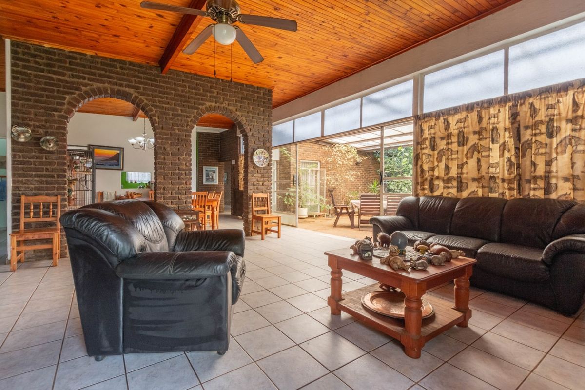 Spacious living area featuring exposed brick arches, a warm timber ceiling, and large sliding glass doors that provide ample natural light and garden access.