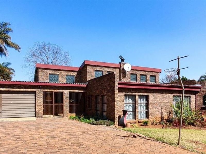 Front elevation of a face brick house featuring a paved driveway, double garage, and secure entrance.