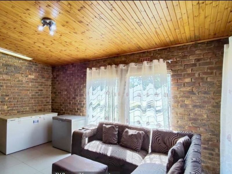 Living room featuring exposed brick walls, a timber tongue and groove ceiling, and tiled flooring.