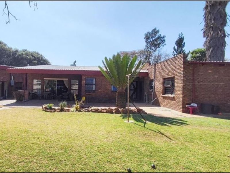 Rear view of a face brick house featuring a covered patio area, sliding glass doors, and a spacious lawn.