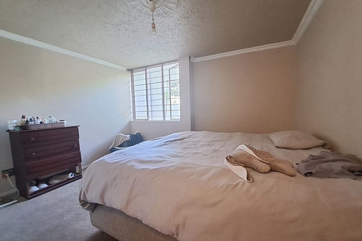 A bedroom featuring a ceiling rose, decorative cornicing, and security bars on the window. The room requires cosmetic updates to the ceiling and flooring.
