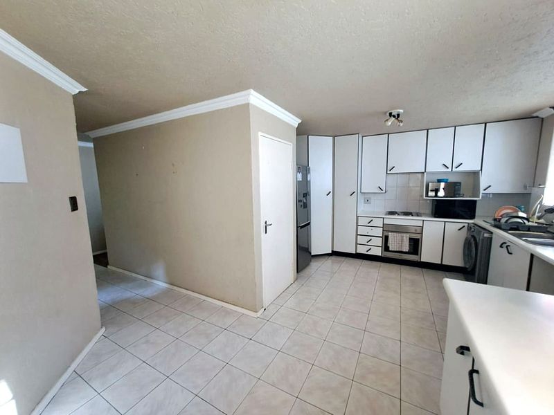 A functional kitchen featuring white cabinetry, built-in oven and hob, tiled flooring, and ample storage space, offering potential for modern updates.