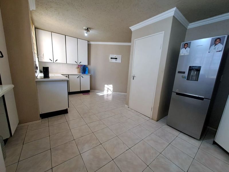 A functional kitchen featuring white built-in cabinetry, tiled flooring, and a coved ceiling, offering a clean and practical layout for daily use.