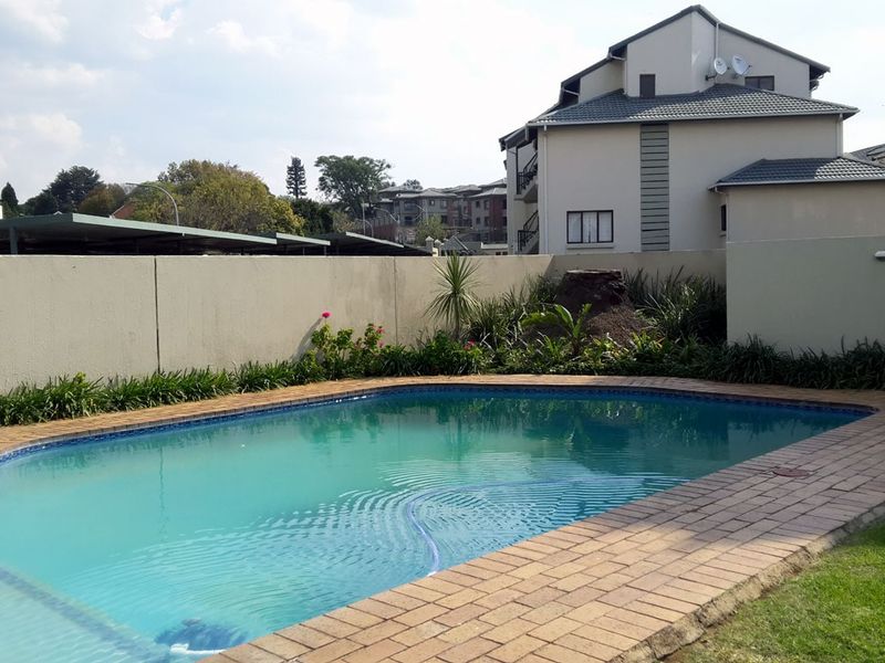 A private swimming pool area featuring brick paving and a surrounding boundary wall, set within a residential apartment complex.