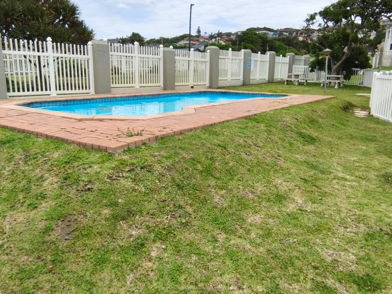 Communal swimming pool area featuring a paved surround and white vinyl perimeter fencing set within a landscaped garden space.