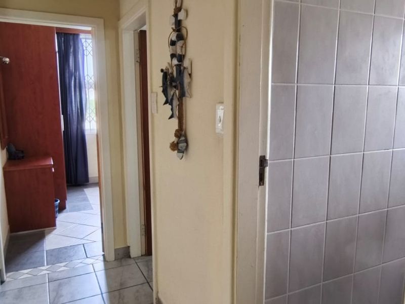 A functional apartment hallway featuring tiled flooring and access to adjacent rooms, providing a neutral transition space within the unit.