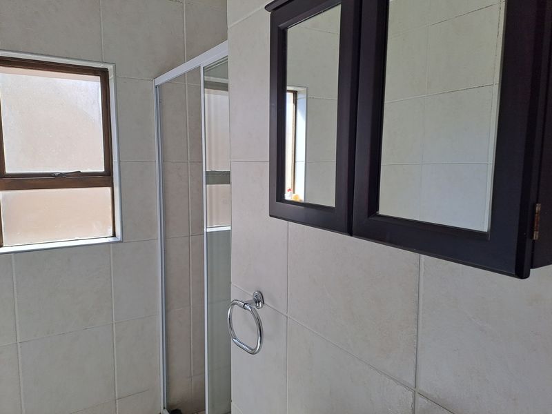 A functional bathroom featuring a shower enclosure, tiled walls, and a wall-mounted medicine cabinet.