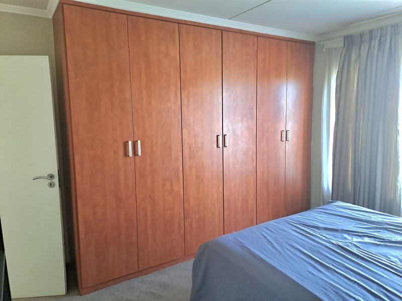 A bedroom featuring extensive floor-to-ceiling built-in wooden cupboards providing ample storage space.
