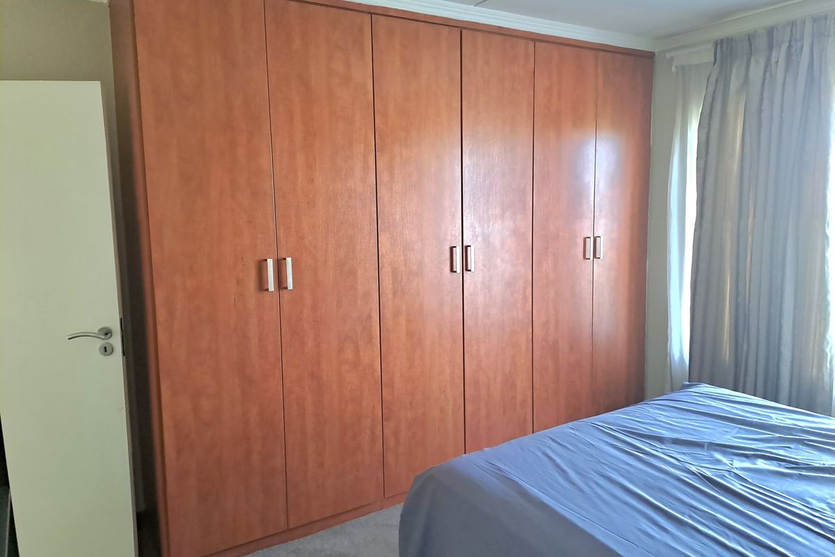 A bedroom featuring extensive floor-to-ceiling built-in wooden cupboards providing ample storage space.