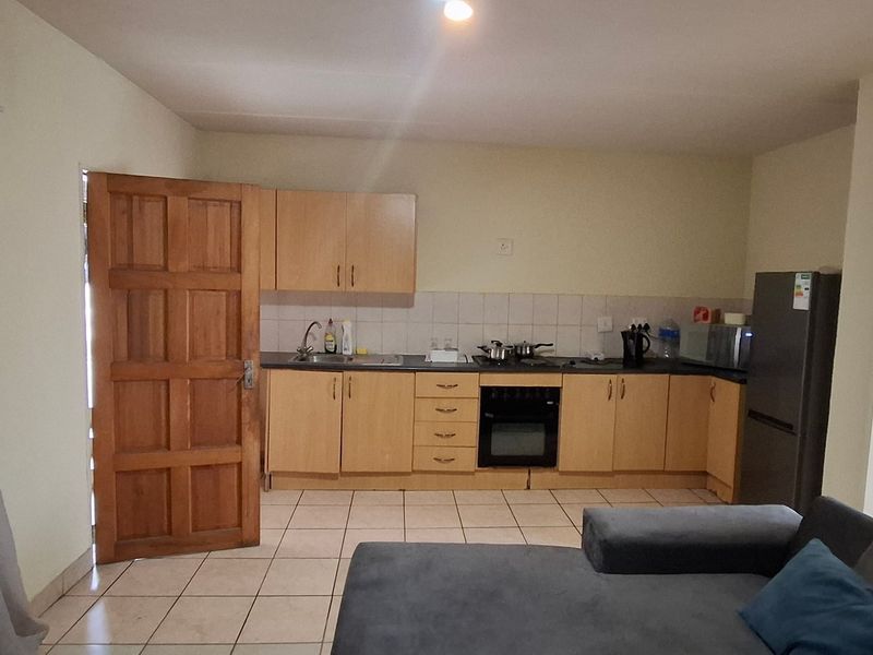Open plan living area featuring a functional kitchen with built-in cabinetry, oven, hob, and tiled flooring throughout.