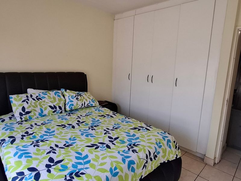 A bedroom featuring built-in cupboards and tiled flooring, offering a functional space with neutral wall finishes.