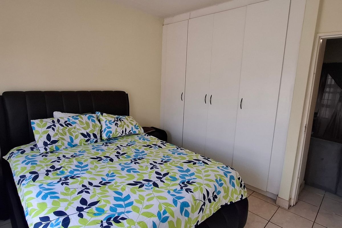 A bedroom featuring built-in cupboards and tiled flooring, offering a functional space with neutral wall finishes.