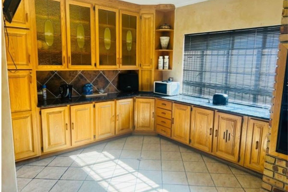 A traditional kitchen featuring extensive oak cabinetry, granite countertops, and tiled flooring, offering a functional layout with ample storage space.