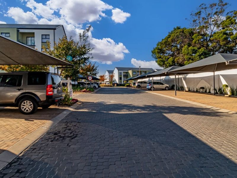 Exterior view of the apartment complex parking area featuring paved driveways and covered shade cloth parking bays.