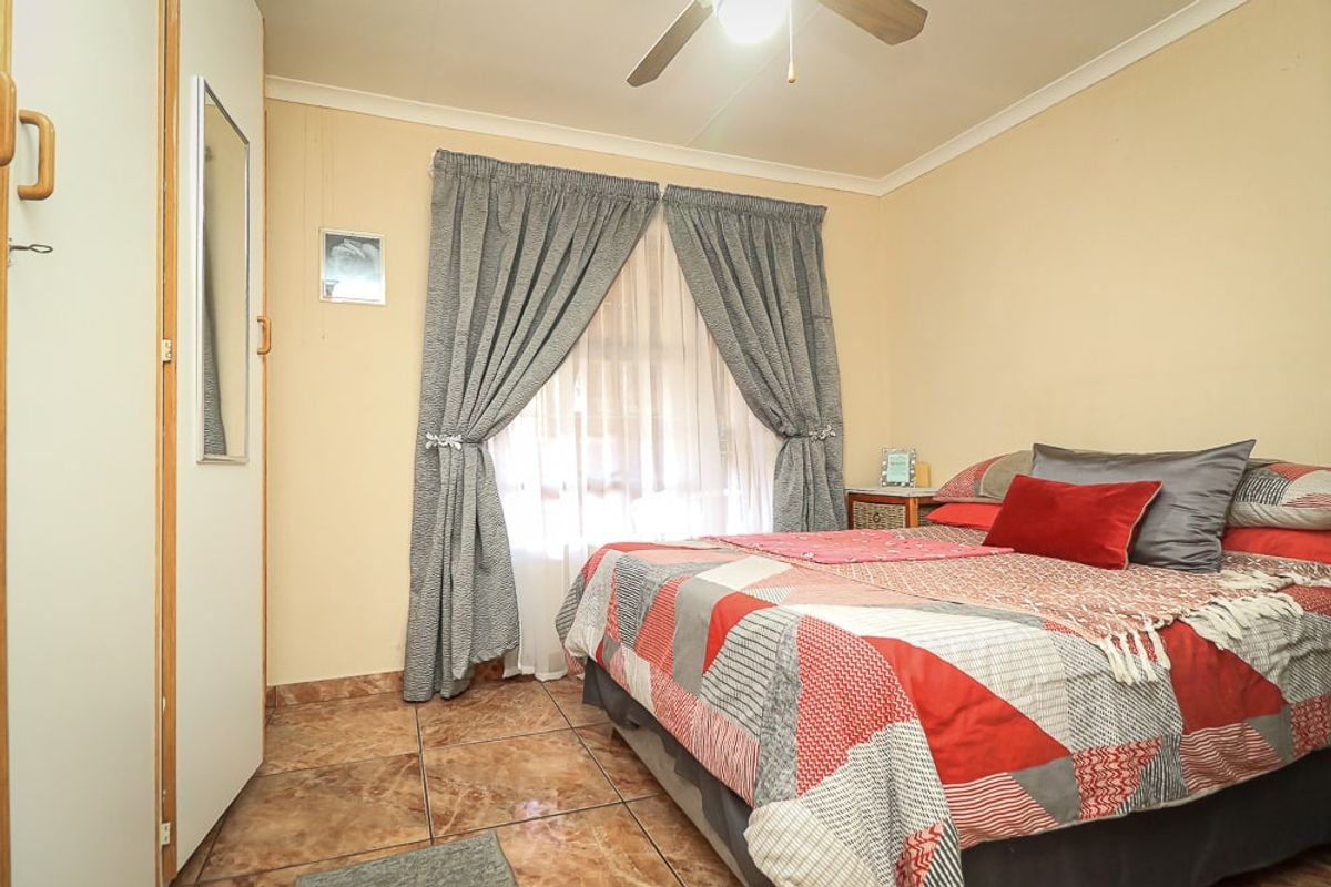 A functional bedroom featuring tiled flooring, a built-in wardrobe, and a ceiling fan, providing a comfortable and practical living space.