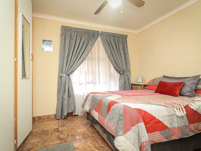 A functional bedroom featuring tiled flooring, a built-in wardrobe, and a ceiling fan, providing a comfortable and practical living space.