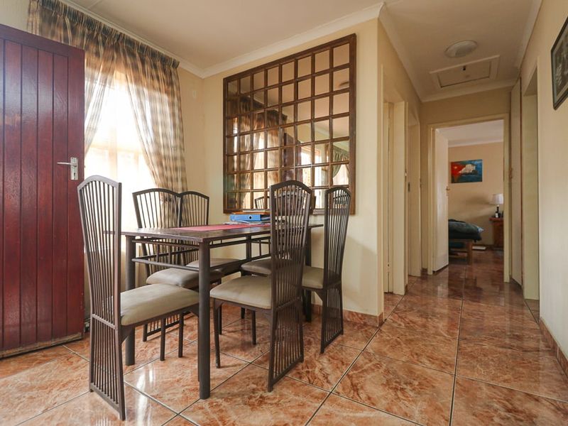 Dining area featuring tiled flooring and a decorative wall mirror, providing access to the hallway and adjacent rooms.