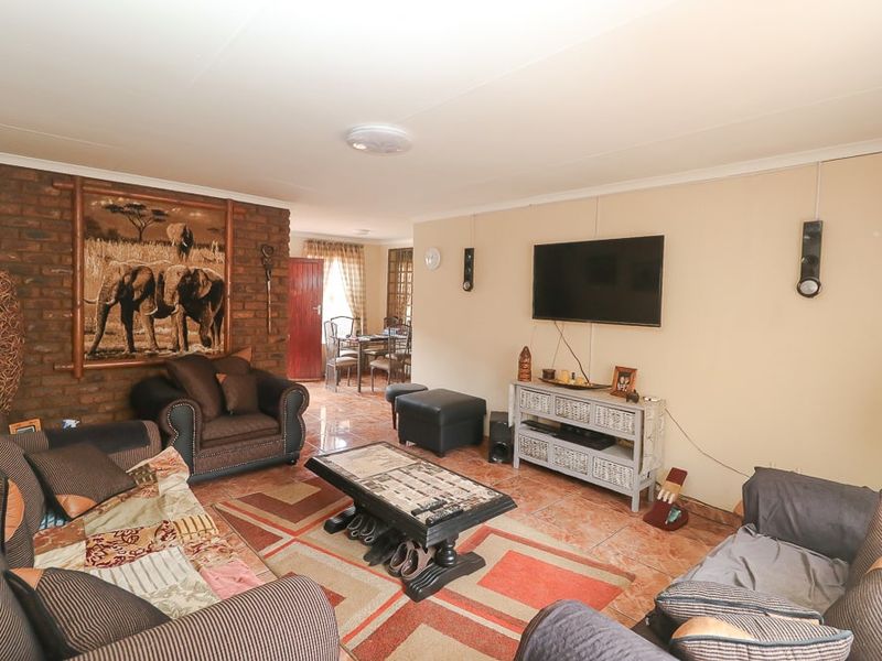 Spacious living area featuring an exposed brick accent wall and tiled flooring, providing a comfortable and functional space for relaxation.