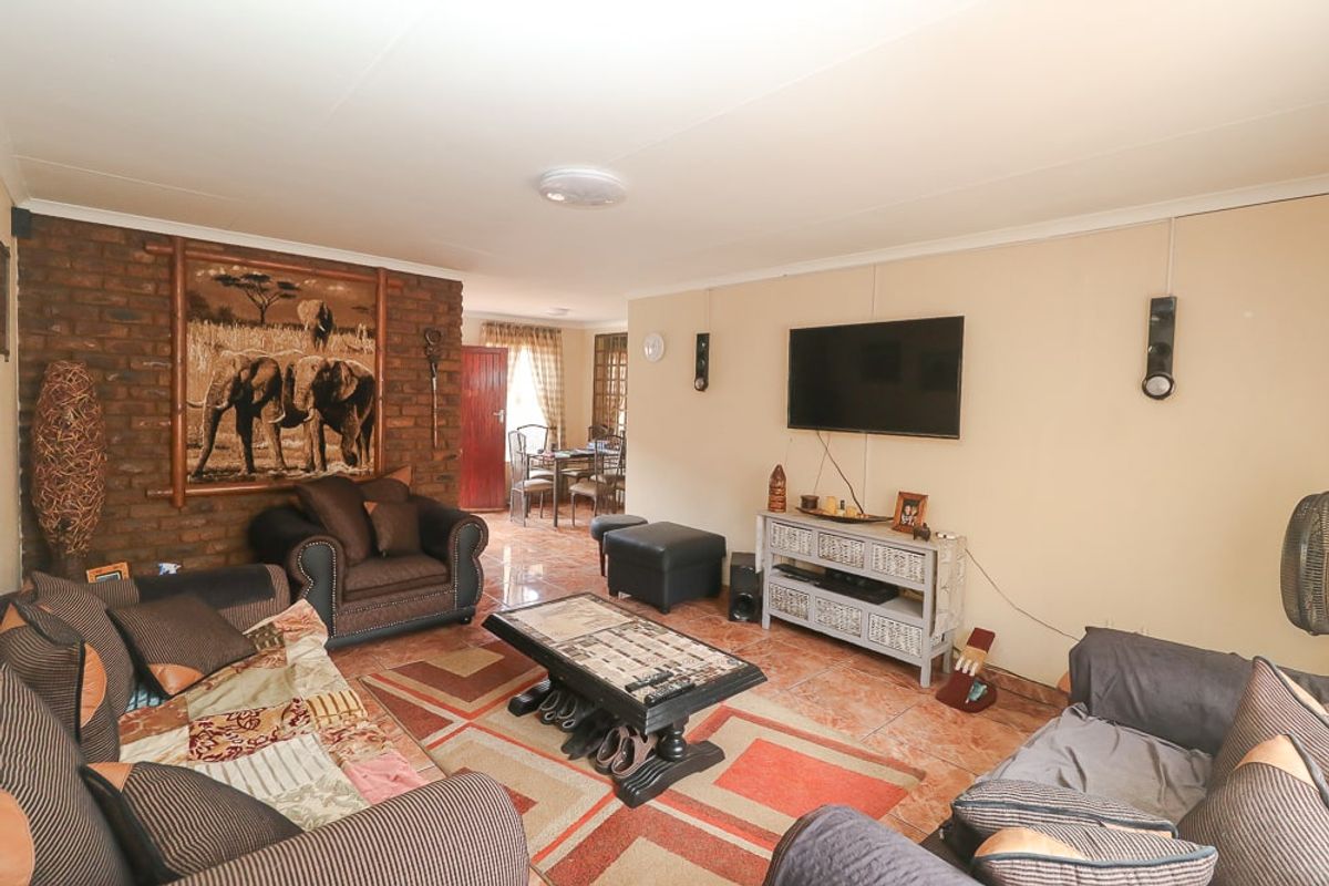 Spacious living area featuring an exposed brick accent wall and tiled flooring, providing a comfortable and functional space for relaxation.