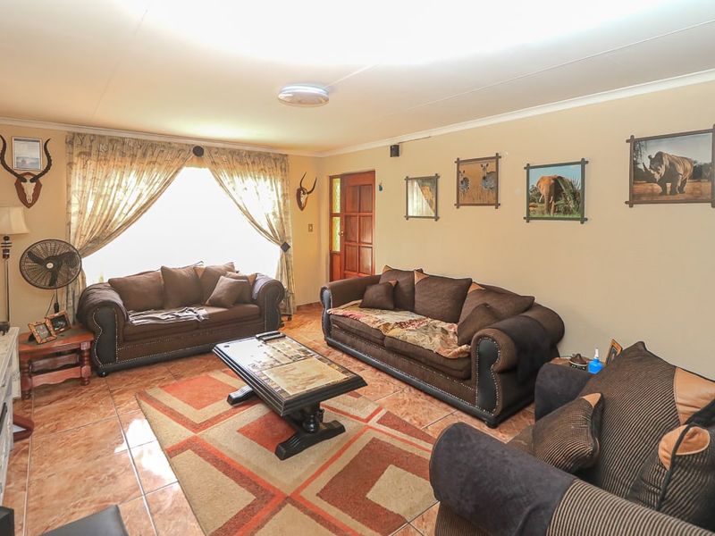 A comfortable living room featuring tiled flooring and a timber entrance door, providing a functional and lived-in space.