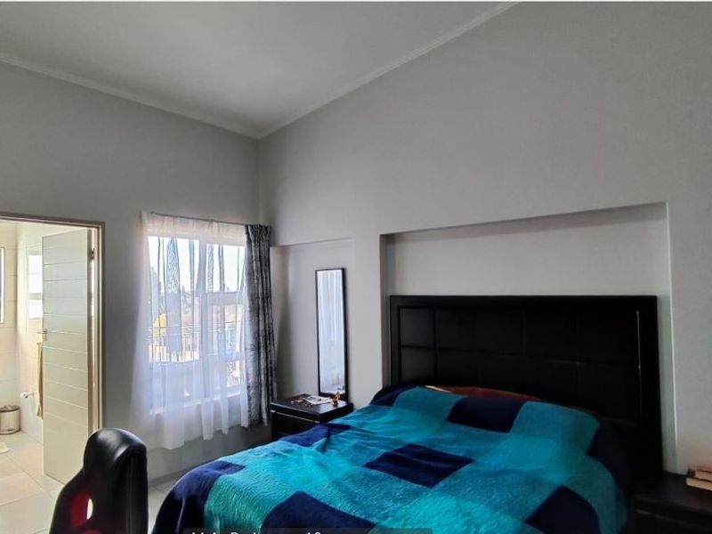 A well-lit bedroom featuring a built-in headboard, recessed wall niche, and direct access to an en-suite bathroom.