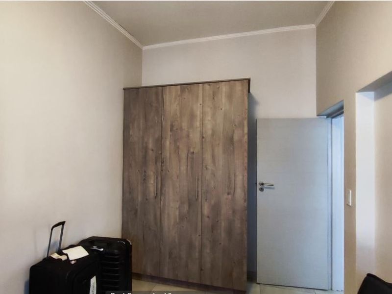 A bedroom featuring a modern wood-finish built-in wardrobe and a neutral interior door, providing clean and functional storage space.