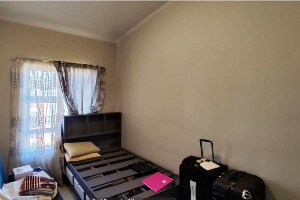 A standard bedroom featuring a window with installed curtain rods and neutral wall finishes.