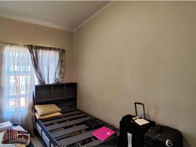 A standard bedroom featuring a window with installed curtain rods and neutral wall finishes.